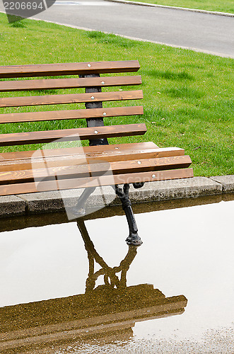 Image of A bench and reflection in the park after the rain