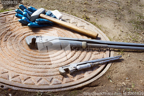 Image of Hammer and wrench are on a manhole