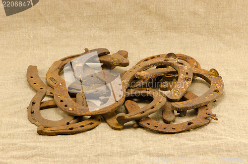 Image of stack old retro rusty horseshoes linen background 
