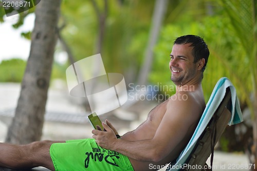 Image of man ralaxing and use tablet at beach