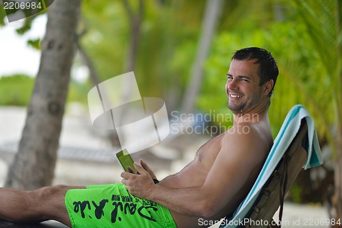 Image of man ralaxing and use tablet at beach