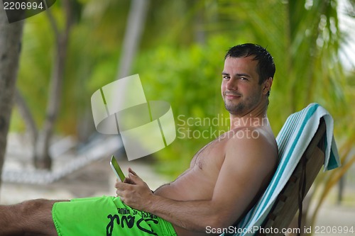 Image of man ralaxing and use tablet at beach