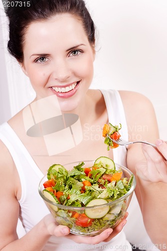 Image of smiling woman eating fresh salad