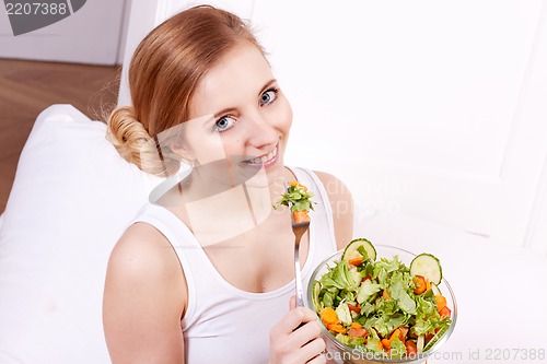 Image of smiling woman eating fresh salad