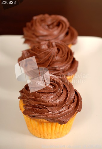 Image of Three chocolate frosted cupcakes in a row