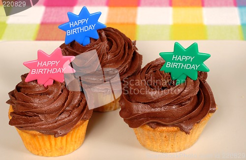 Image of Closeup of three chocolate frosted cupcakes with "Happy Birthday