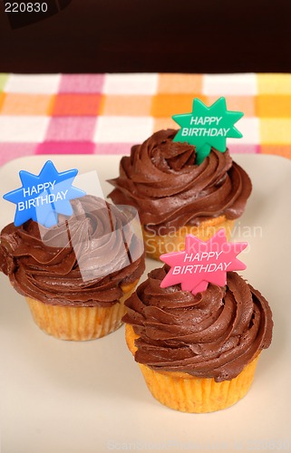 Image of Three chocolate frosted cupcakes with "Happy Birthday" on them