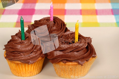 Image of Three chocolate frosted cupcakes with candles