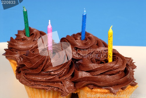 Image of Four chocolate frosted cupcakes with candles