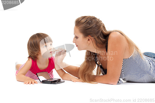 Image of Young mother paints lipstick little daughter in the studio