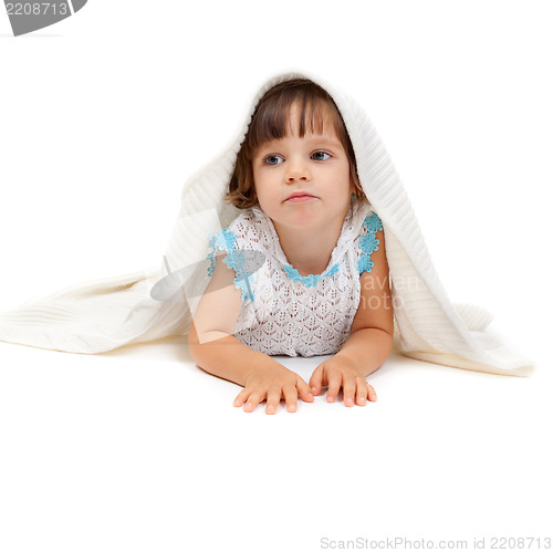 Image of Thoughtful little girl lying on the floor wrapped in a light bla
