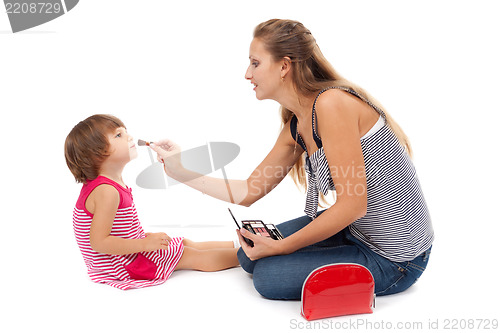 Image of Young mother paints little girl cosmetics