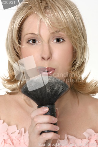 Image of Female flowing excess powder from makeup  brush