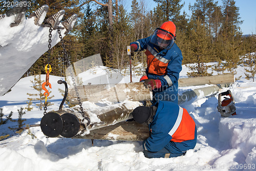 Image of Installers collect a power pole in the snow