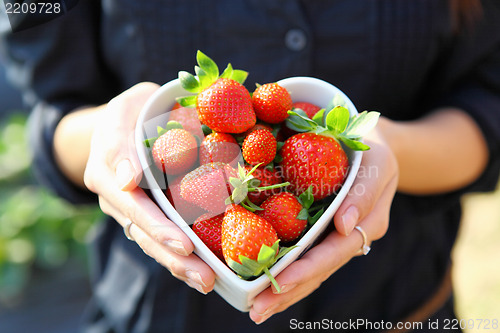 Image of strawberry in heart shape bowl with hand