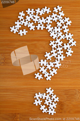 Image of question mark made by puzzle on wood background