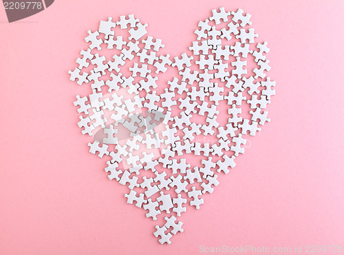 Image of puzzle made heart sharp on pink background