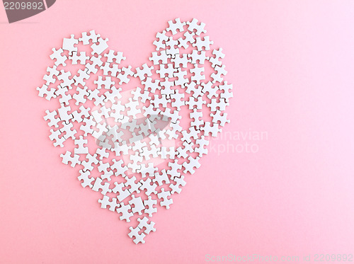 Image of puzzle made heart sharp on pink background