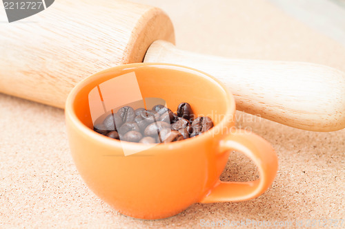 Image of Cup of roast coffee bean and roller on cork background