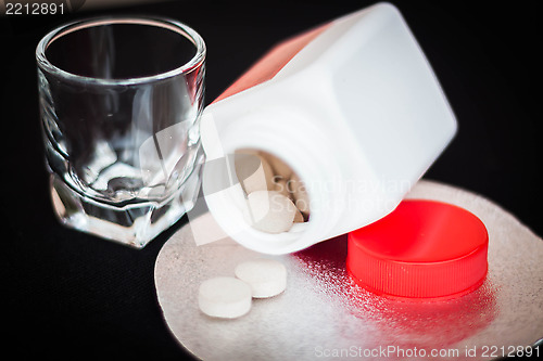 Image of Open pill bottle with brown medicine spilling out  