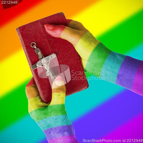 Image of Old hands holding a very old bible, rainbow flag pattern