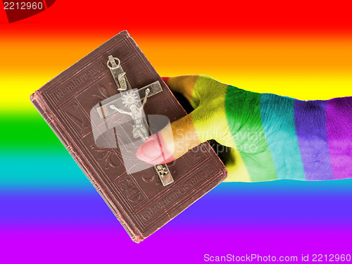 Image of Old hand (woman) holding a very old bible, rainbow flag