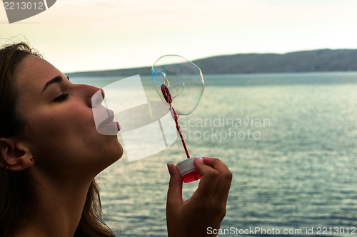 Image of Young woman blowing bubbles