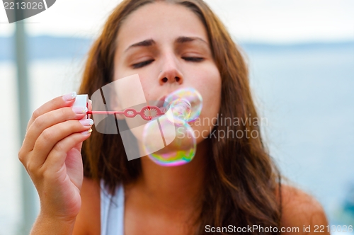 Image of Young woman blowing bubbles