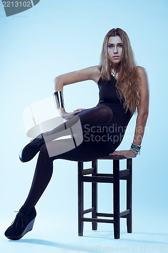 Image of Young blonde woman in black swimsuit sitting on chair posing