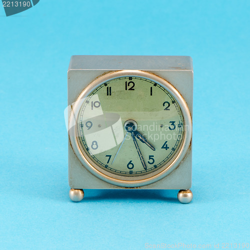 Image of grunge metallic retro clock stand blue background 