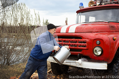 Image of Driver of the water washes the old fire truck