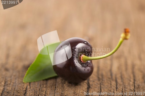 Image of Red, ripe, juicy cherry and leaf on wooden boards