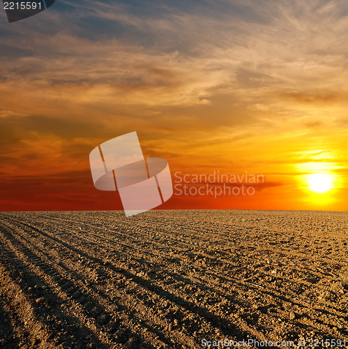 Image of red sunset over ploughed farm field