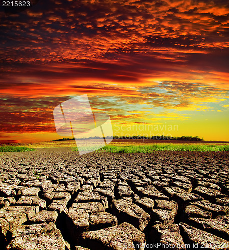 Image of red dramatic sunset over dry cracked earth