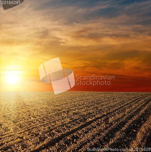 Image of red sunset over ploughed farm field