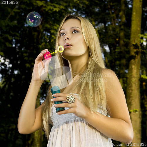 Image of blonde blowing soap bubble