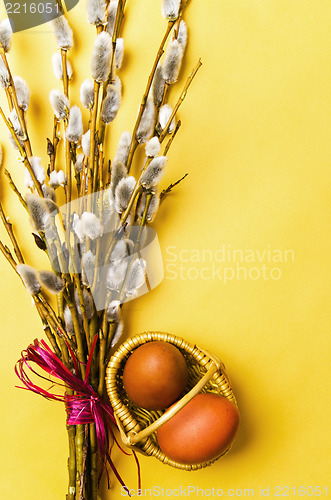 Image of bunch of willow branches and two Easter eggs in basket 