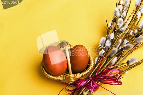 Image of bunch of willow branches and two Easter eggs in basket 