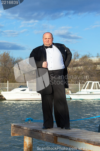 Image of Fat man in tuxedo on pier