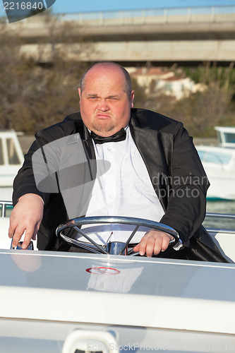 Image of Overweight man in a tuxedo at the helm of a pleasure boat
