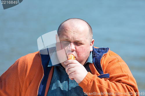 Image of Fat man eating a carrot