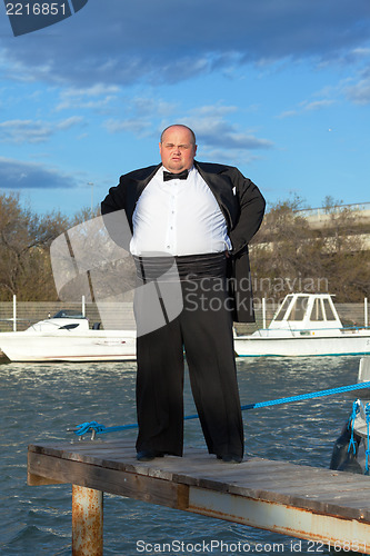 Image of Fat man in tuxedo on pier