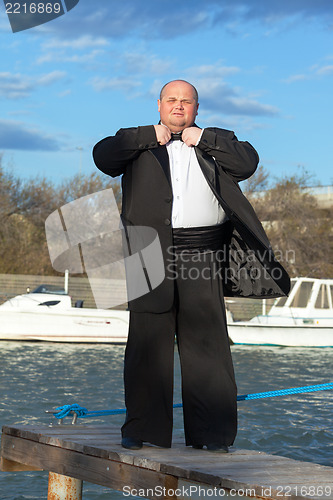 Image of Fat man in tuxedo on pier