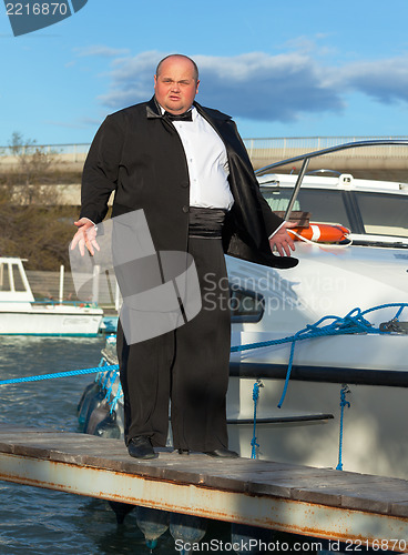 Image of Fat man in tuxedo on deck boat