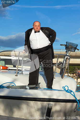 Image of Fat man in tuxedo on deck boat