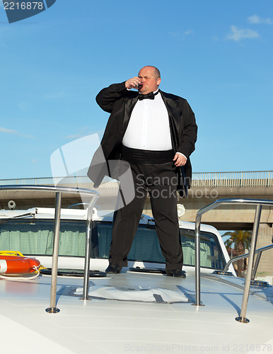 Image of Fat man in tuxedo with glass wine