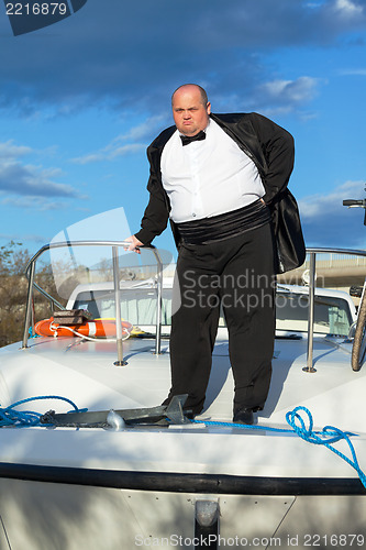 Image of Fat man in tuxedo on deck boat