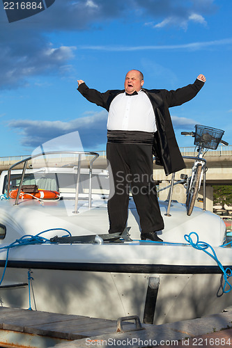 Image of Fat man in tuxedo on deck boat