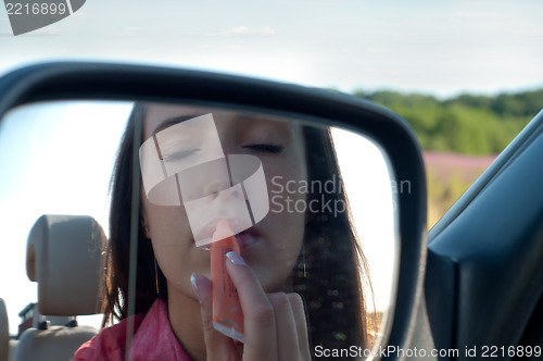 Image of Beautiful brunette woman paints lips with lipstick