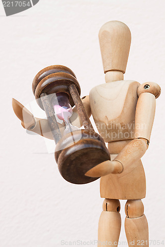 Image of Wood mannequin and hourglass to represent time giving